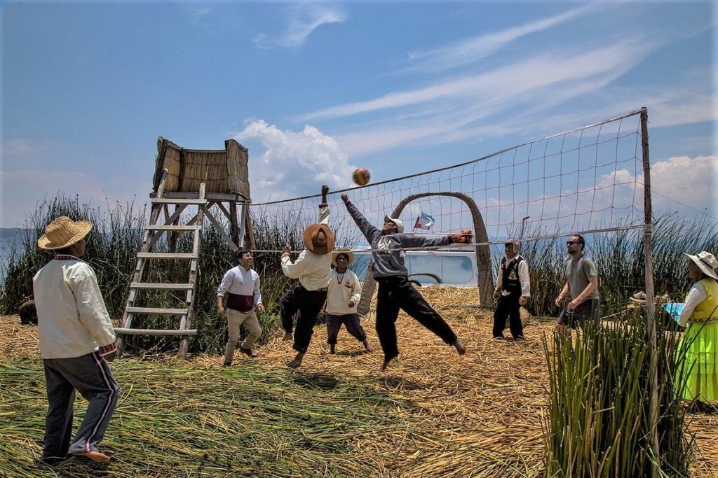 Tourists and locals playing volleybal together on the floating island of Uros Titino on Lake Titicaca, Peru