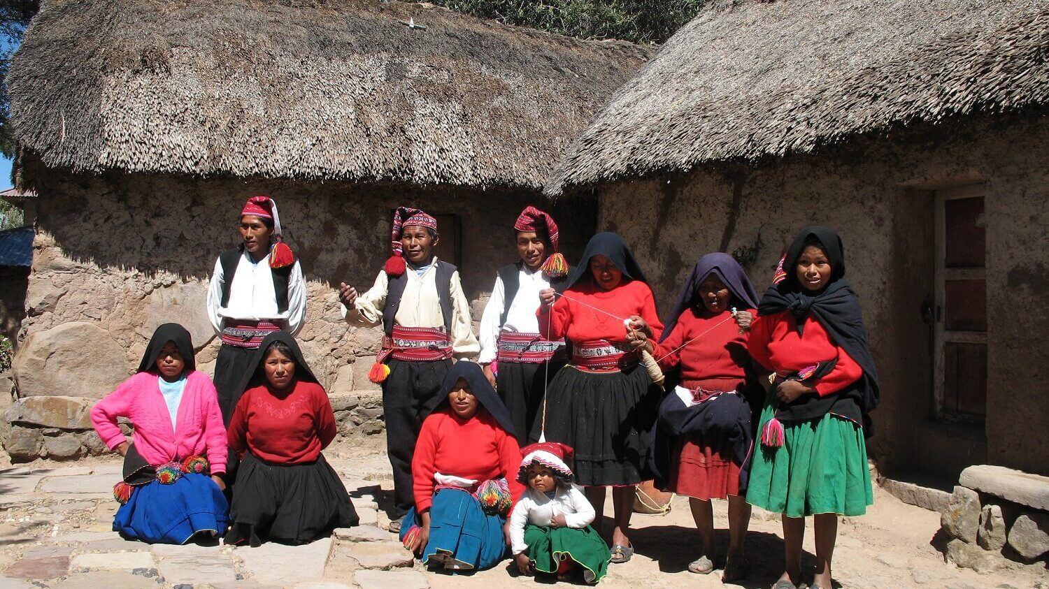Group picture of tourism committee on Taquile island, local men and women wearing traditional dresses. Community-Based Tourism in Peru with RESPONSible Travel Peru.