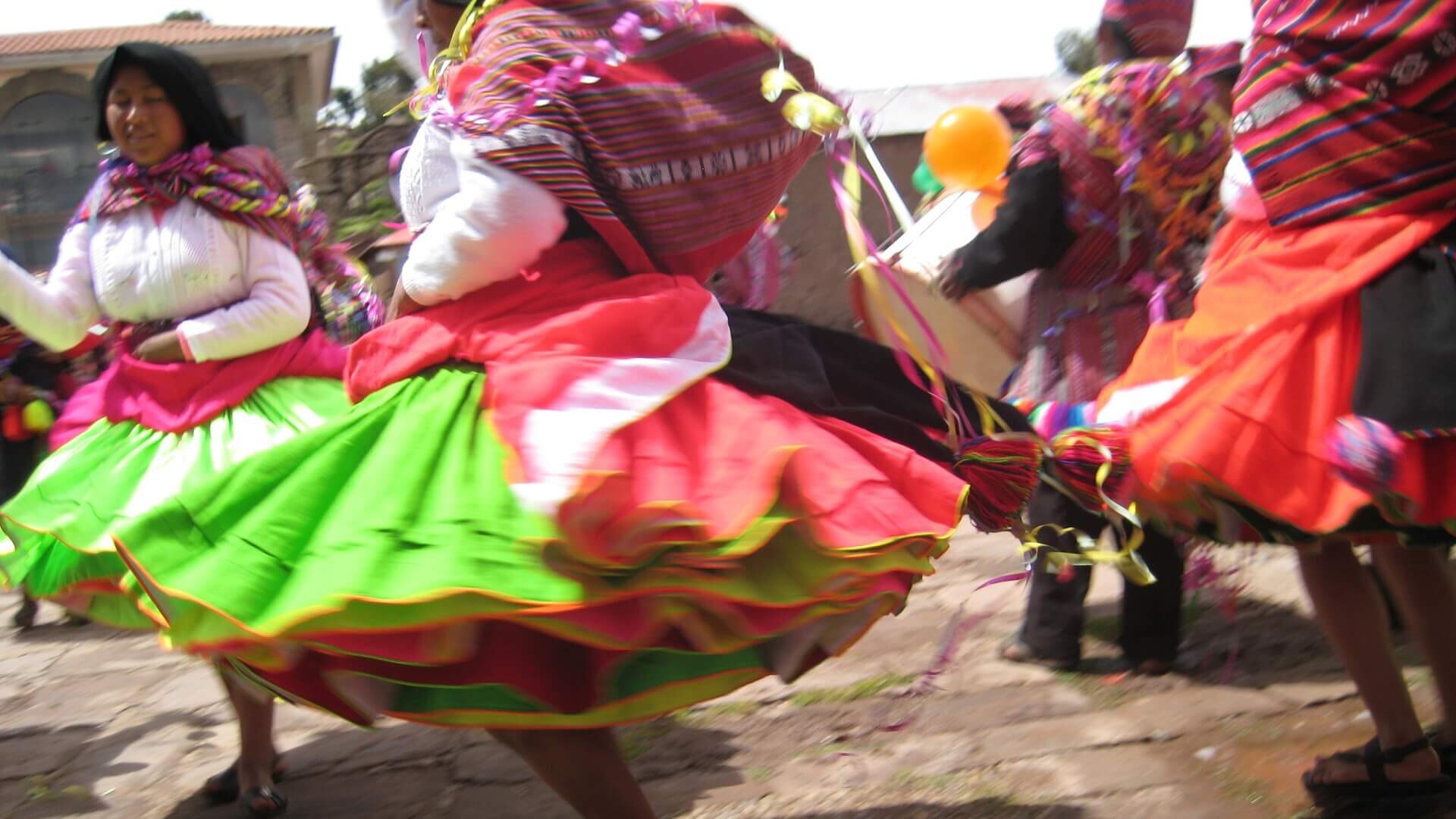 Colorful traditional dresses worn by dancing women at a traditional fiesta on Taquile island, Lake Titicaca, Peru. | RESPONSible Travel Peru