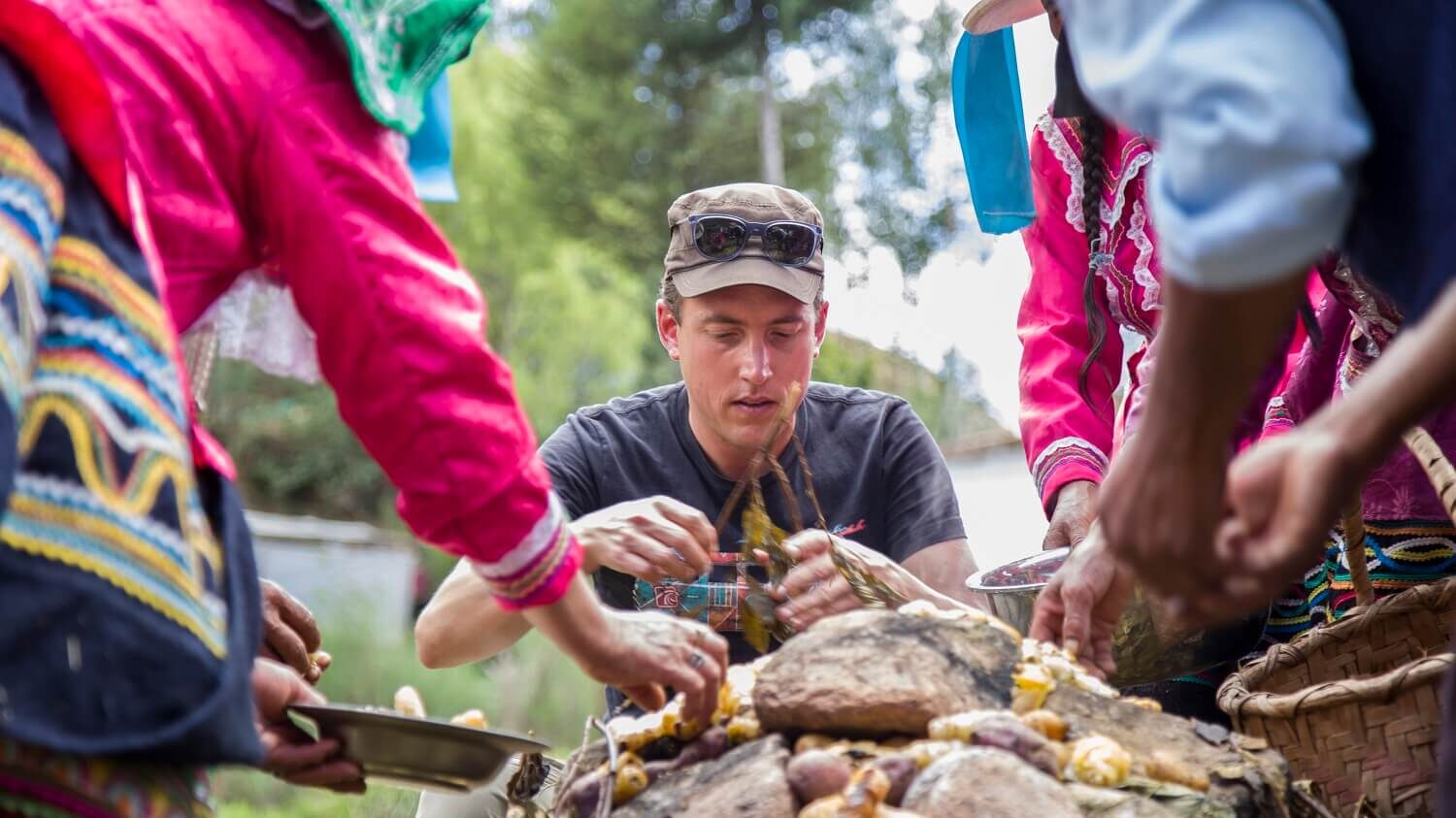 Guido assisting the locals in Vicos with opening the Pachamanca and gathering the freshly cooked potatoes. Community-Based Tourism in the Andes - RESPONSible Travel Peru