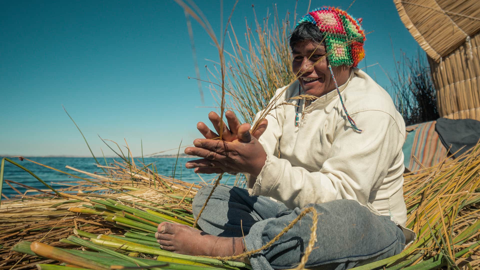 11Man sitting on island floor while using hands and feet when making totora strands | Responsible Travel Peru