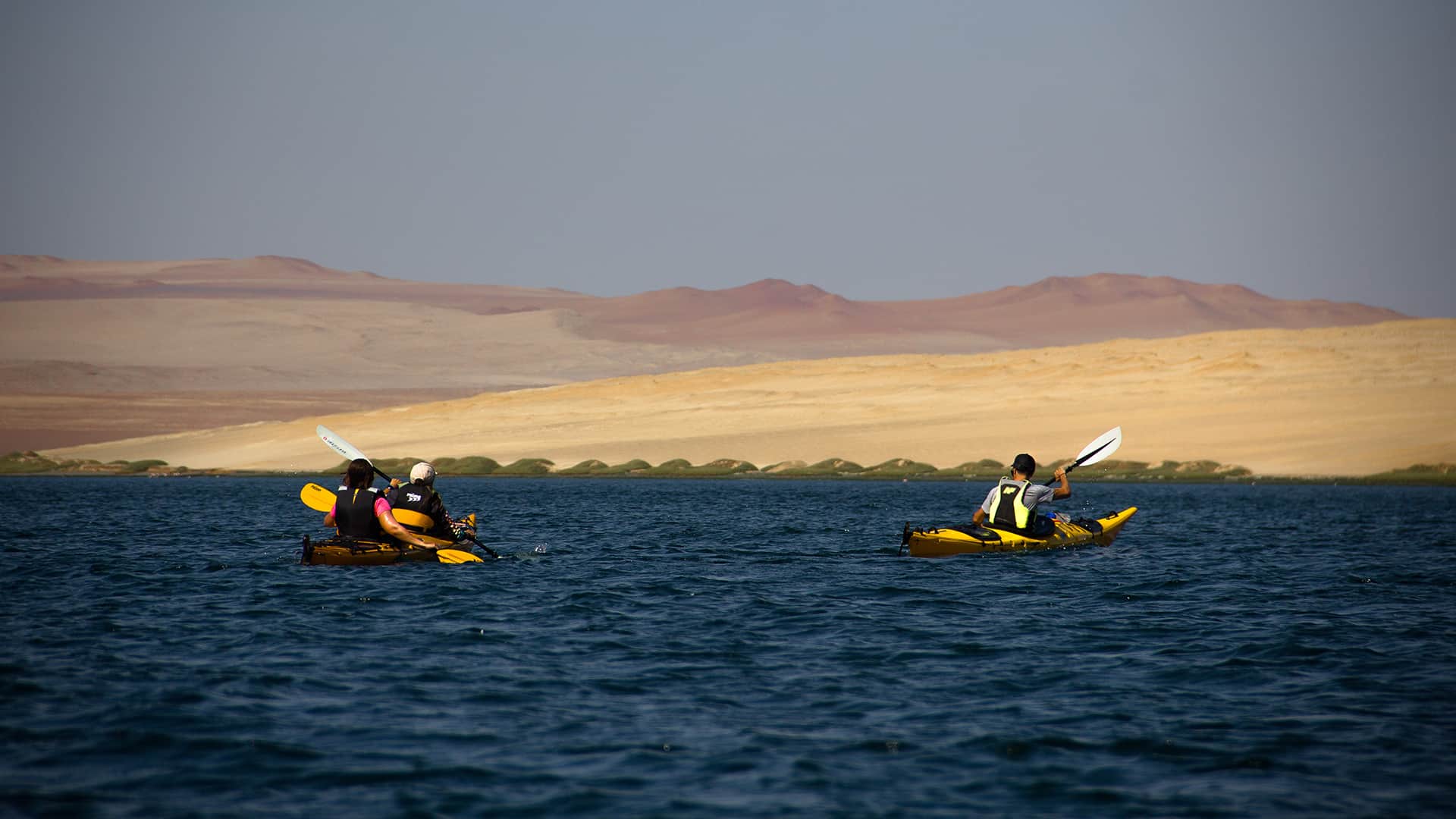 11two kayaks cruising over deep blue waters and montanous desert in the back | Responsible Travel Peru