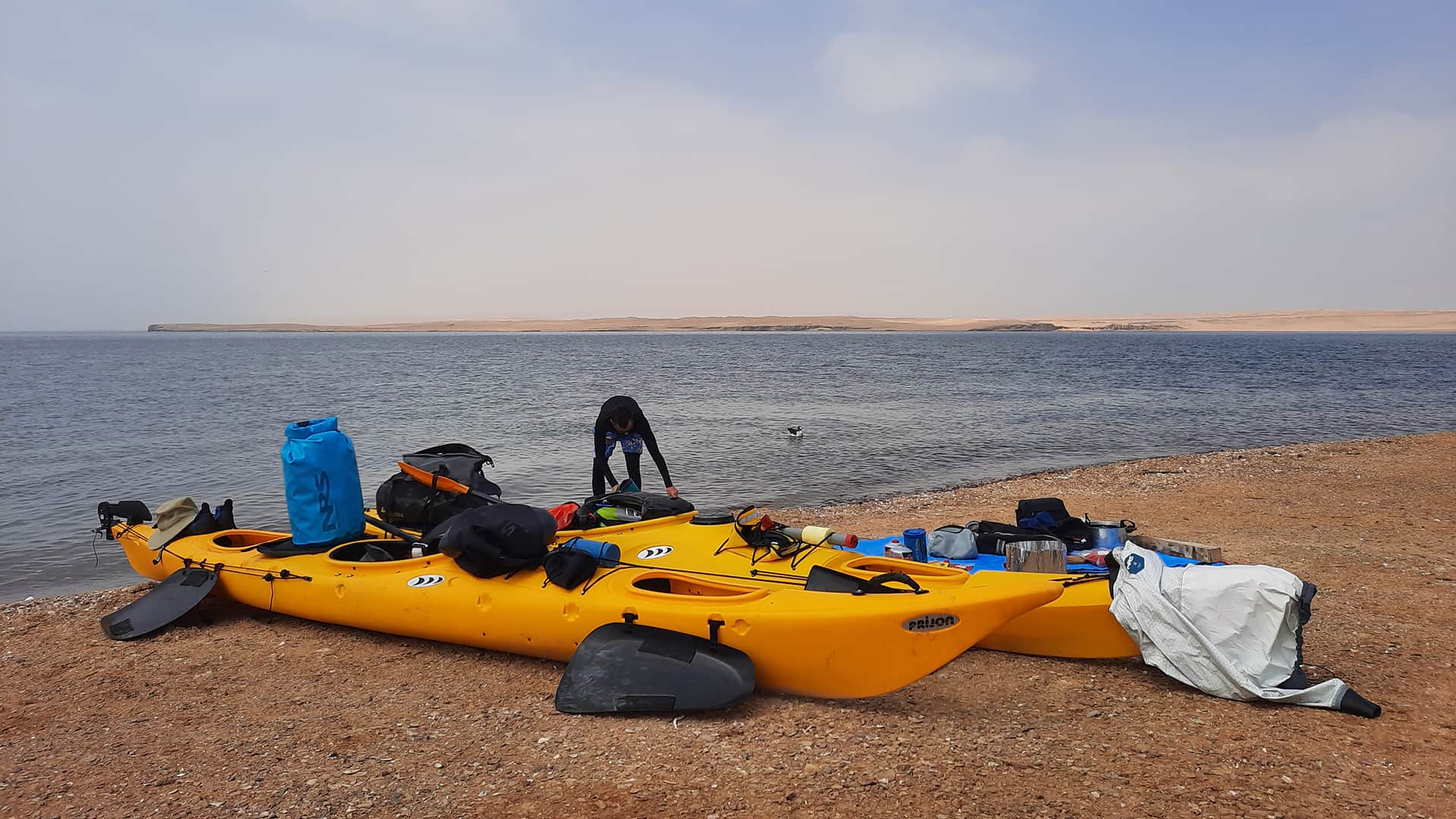 11Kayaks and equipment stationed on the beach checked by man | Responsible Travel Peru