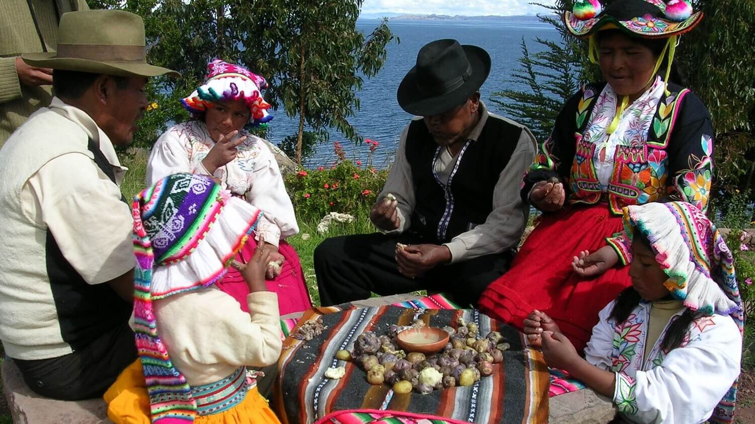 Local inhabitants of Llachón wearing typical clothes enjoying a potatoe lunch. Community-Based tourism in Puno with RESPONSible Travel Peru