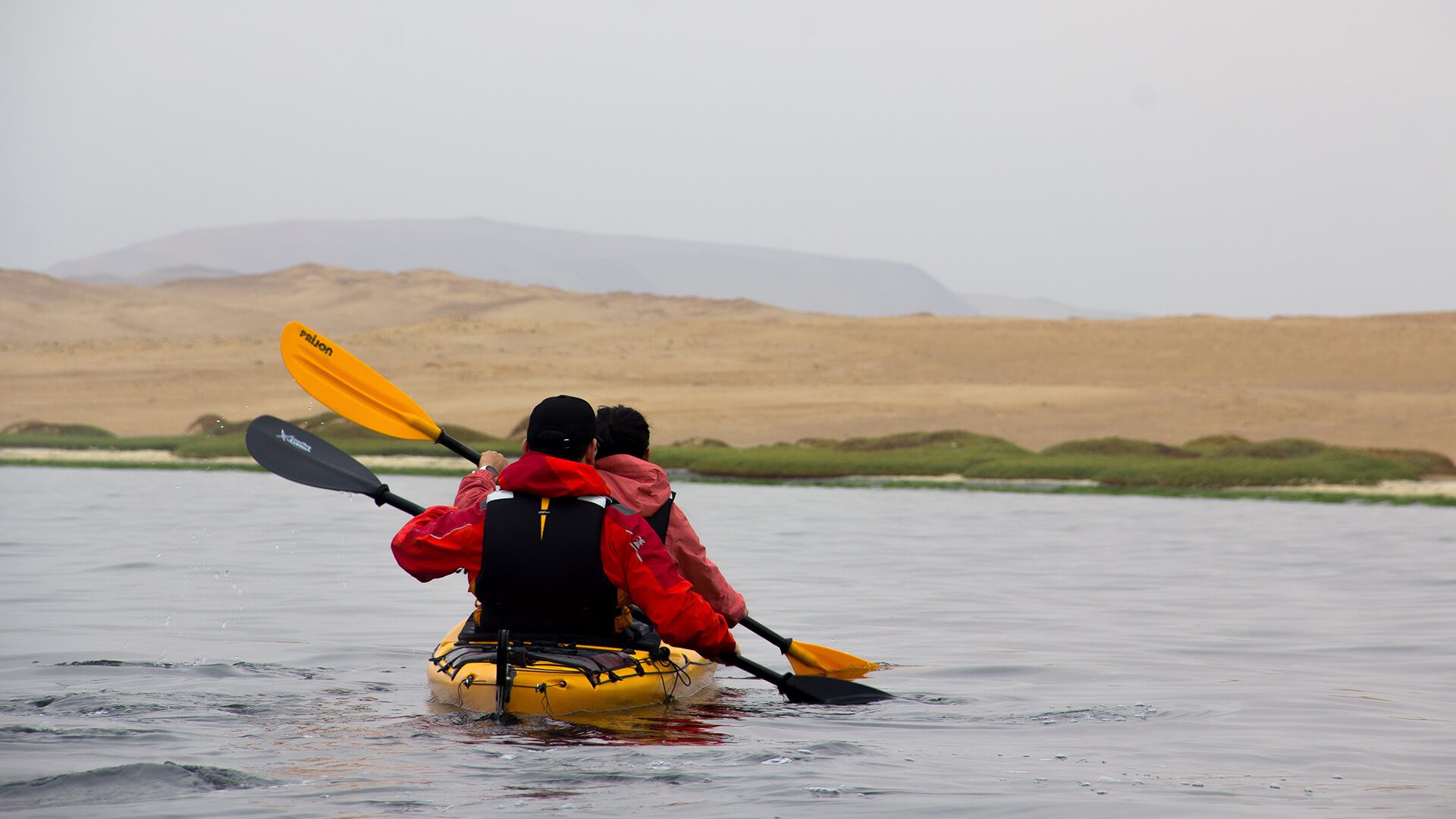 Tandem kayak paddling towards the shore with two horizons in the background - RESPONSible Travel Peru
