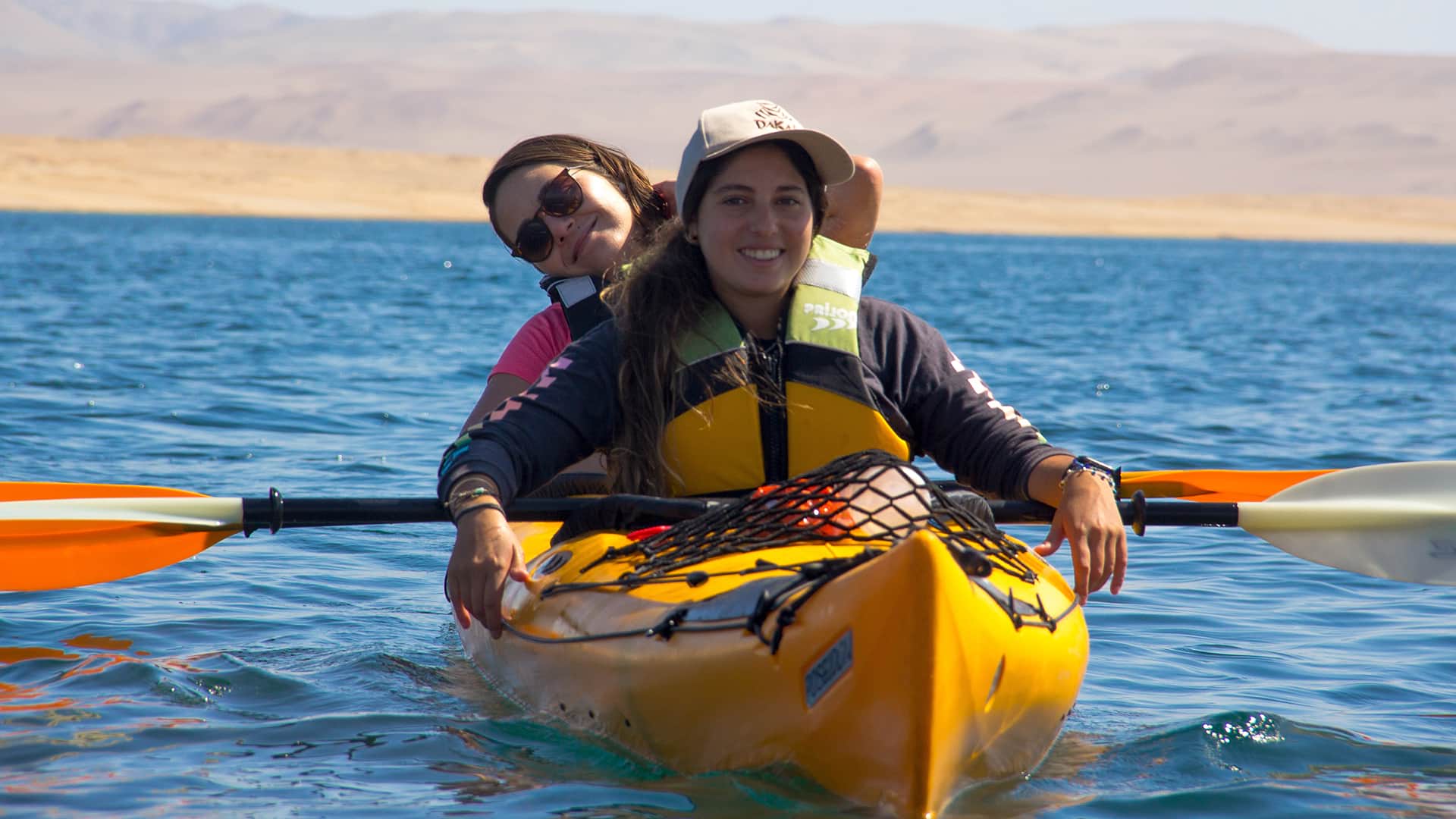 11Two girls chilling in kayak over blue water an desertic background | Responsible Travel Peru