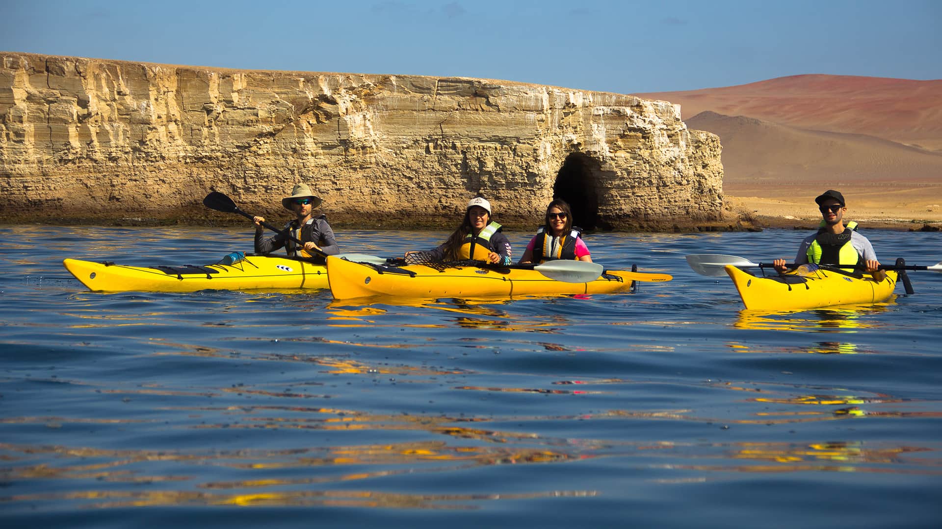 11Three bright yellow kayaks over deep blue waters, mountain desert and rock formation in the background | Responsible Travel Peru
