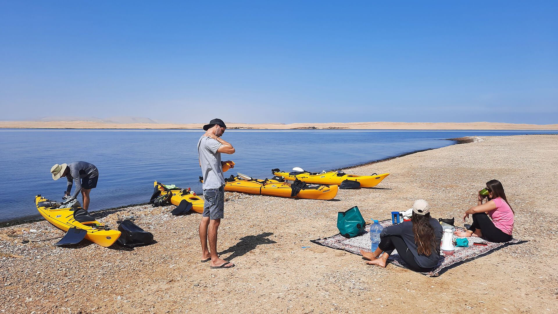 Two girls and two guys off kayaks at the beach brunching - RESPONSible Travel Peru