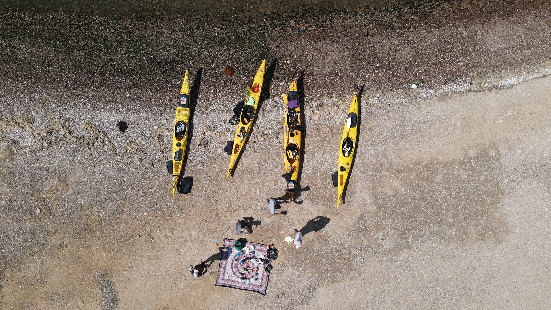 Aerial view of four stationary kayaks and people around the picnic set up - RESPONSible Travel Peru