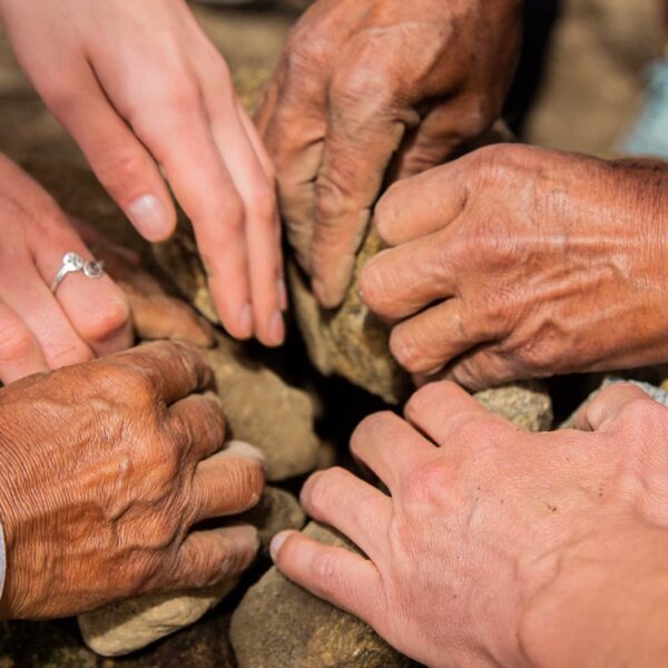 Multiple hands piling rocks for a Pachamanca oven | RESPONSible Travel Peru