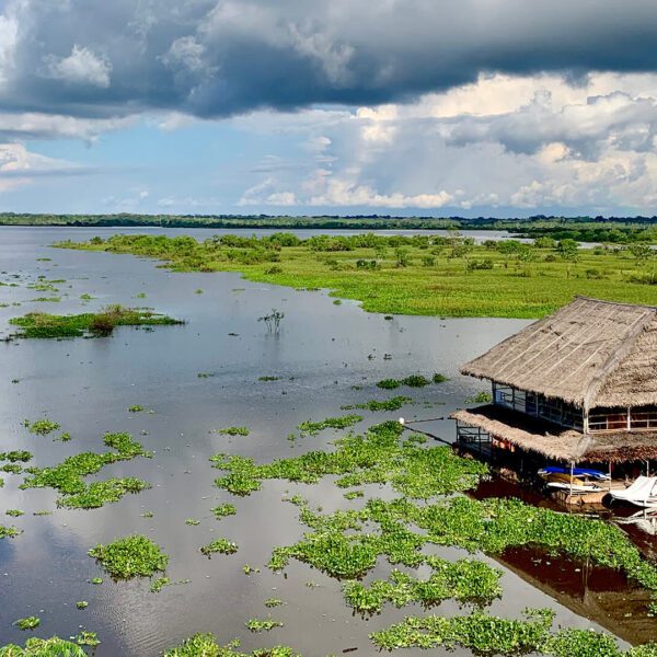 Iquitos landscape with a stilt house over the river, surrounded by vegetation and powerful clouds