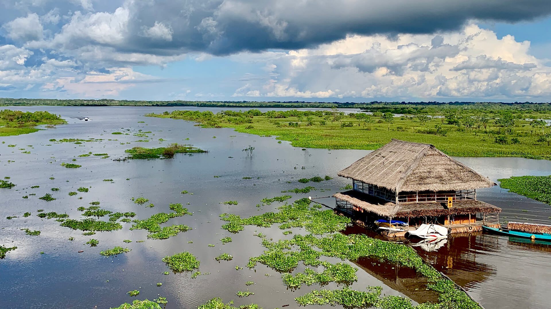 11Iquitos landscape with a stilt house over the river, surrounded by vegetation and powerful clouds