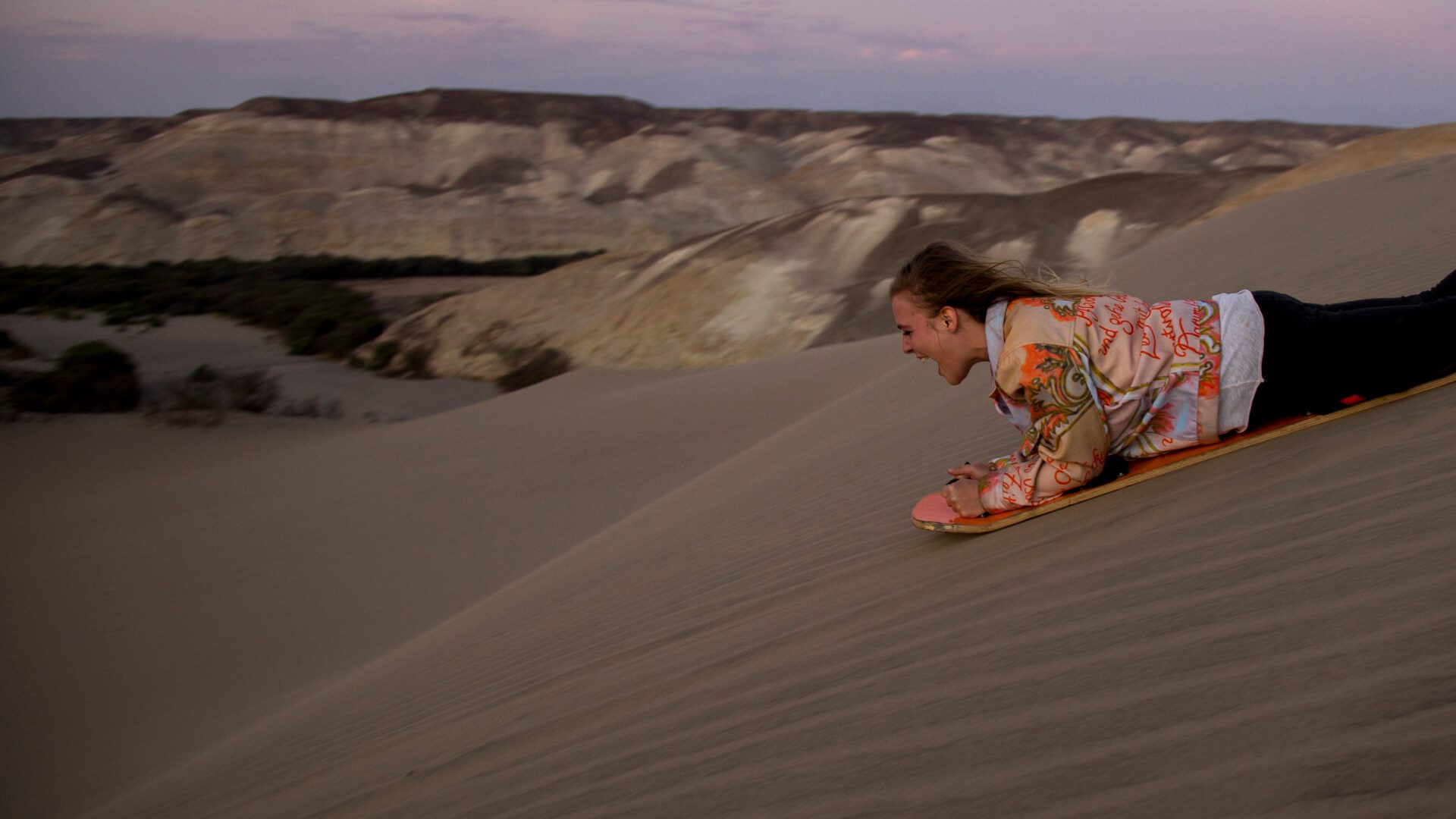 11Girl sandboarding down a dune in the Nazca desert | RESPONSible Travel Peru