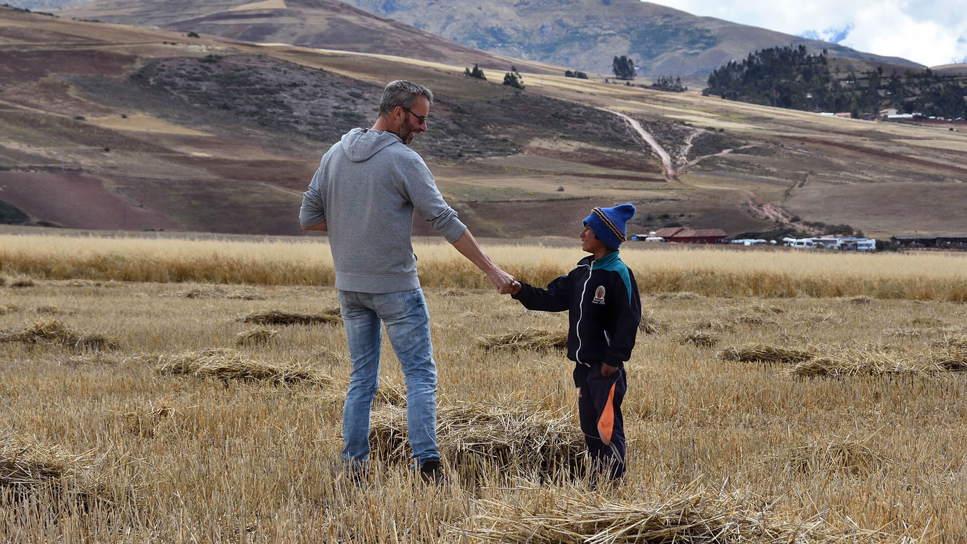Adult and child shaking hands on Peruvian landscape