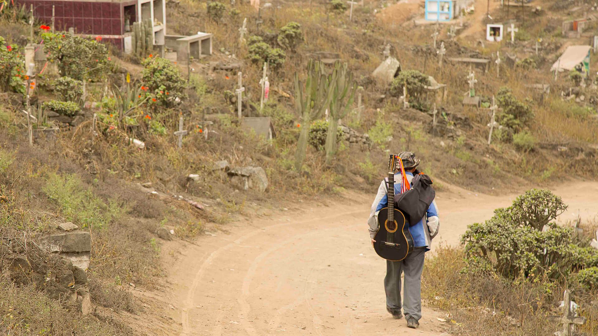 11Guitar player walking on a dirt road of the Nueva Esperanza cemetery in Lima | RESPONSible Travel Peru