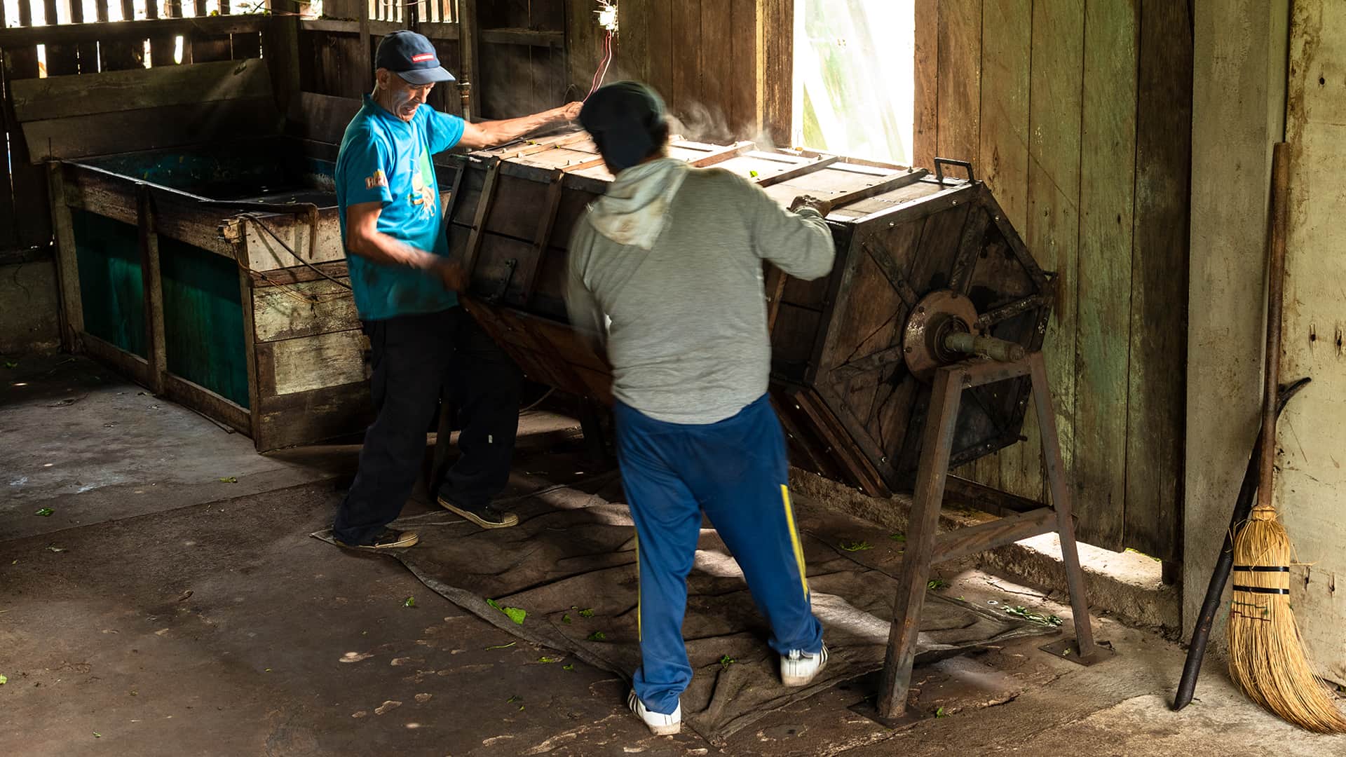 Two men moving a "barrel" as part of the tea processing