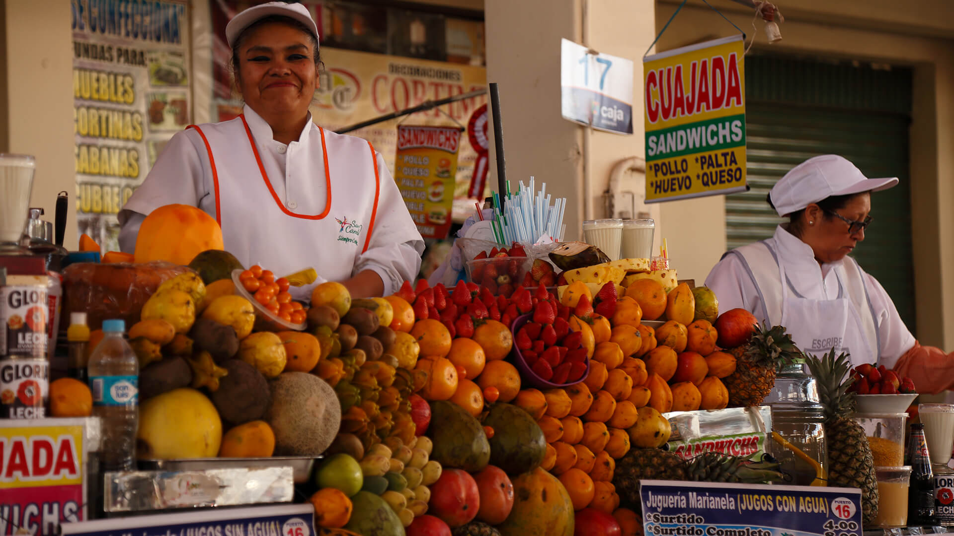 Juice ladies surrounded by tons of fruit at their stands in the market of San Camilo, Arequipa - RESPONSible Travel Peru