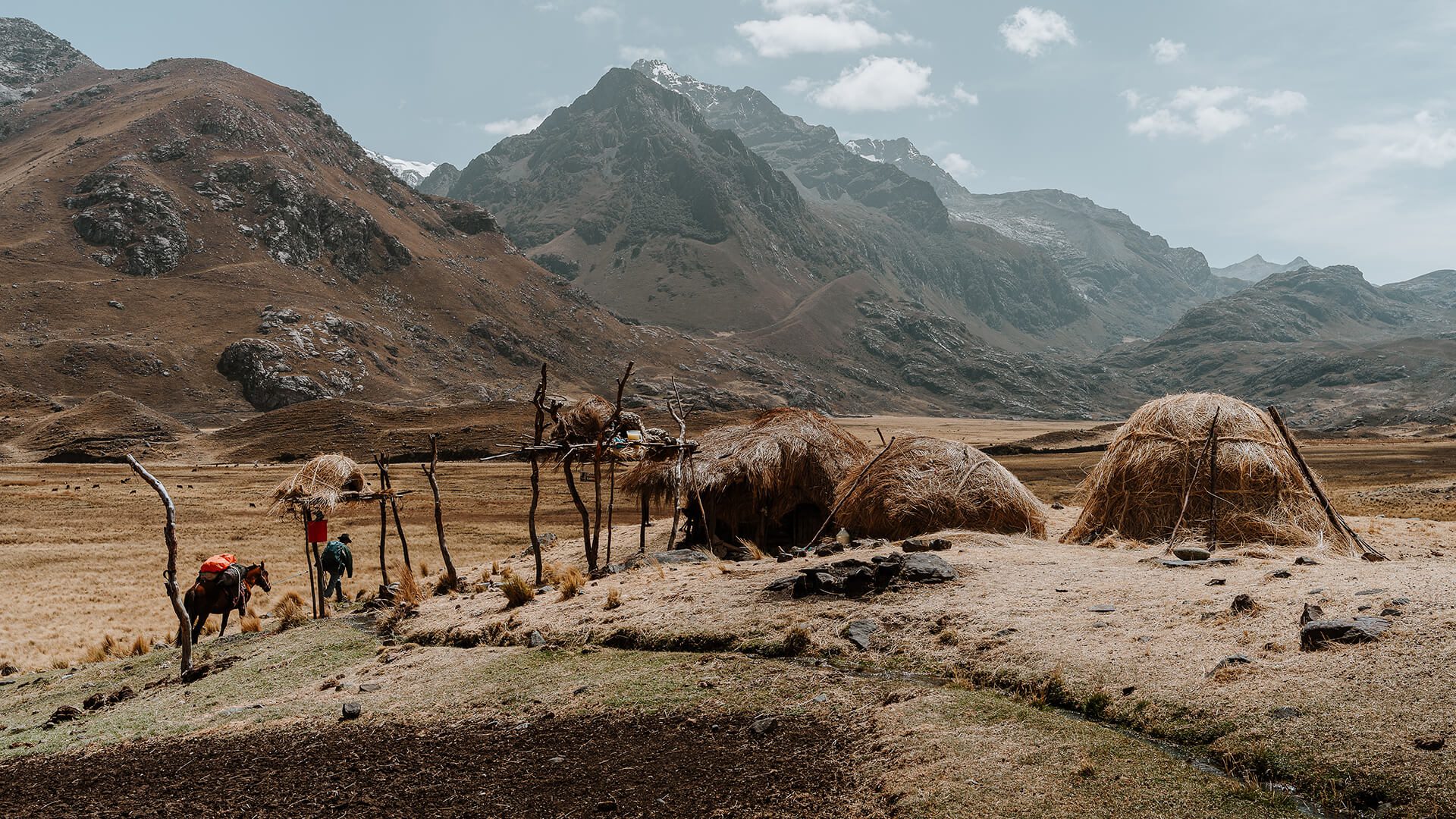 Man, horse, grass-roofed huts in an Andean mountain scenery | Llama Trek Olleros to Chavin with RESPONSible Travel Peru | Photo by Bjorn Snelders