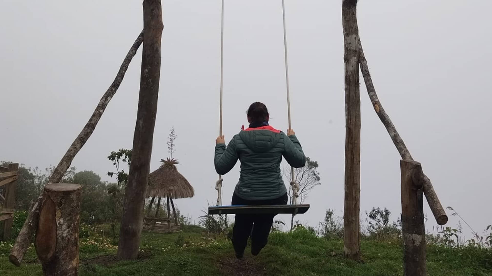 Woman on a rustic swing on top a mountain