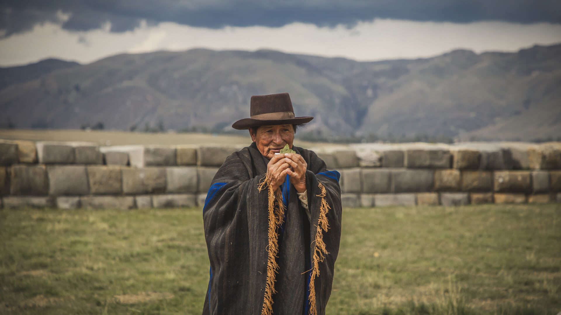 An Andean man is performing a traditional Pachamama blessing ceremony on top of the ushnu temple in Huanuco Pampa, Peru | Hike the Inka Naani with RESPONSible Travel Peru